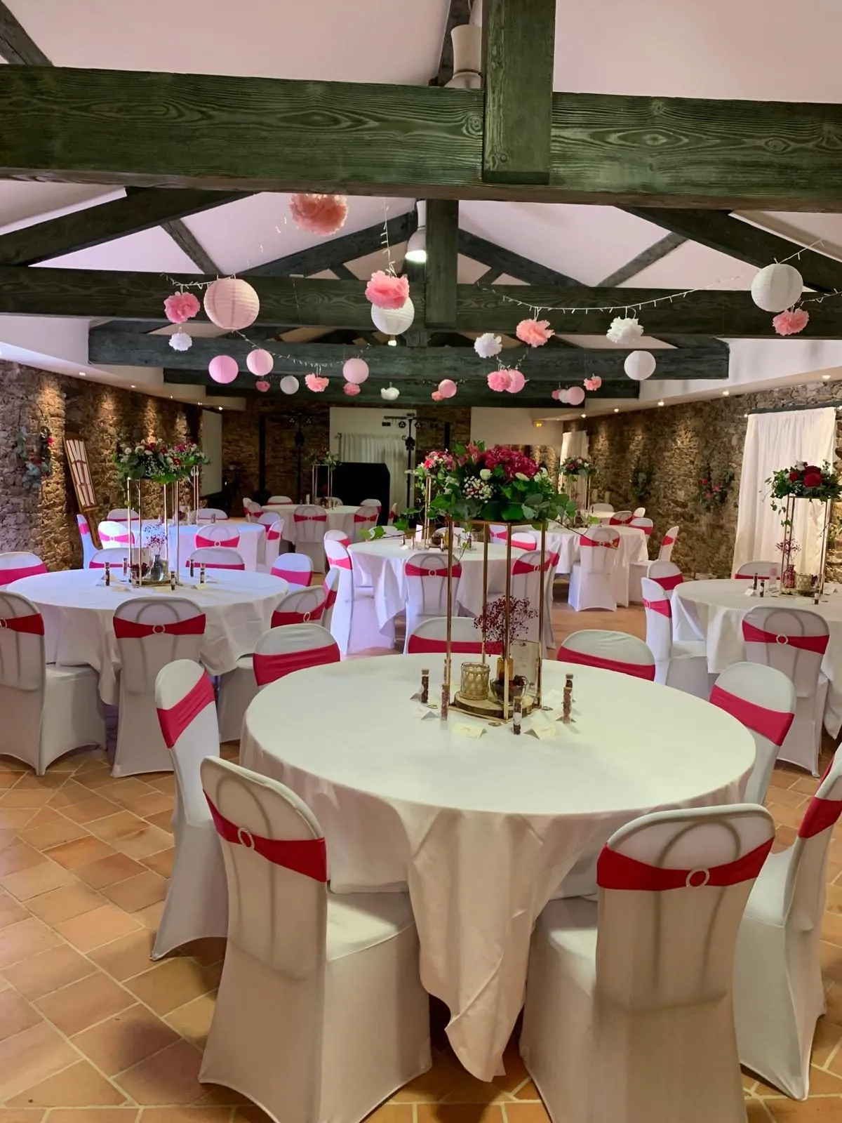 Salle de réception décorée de lanternes et de fleurs roses pour un mariage